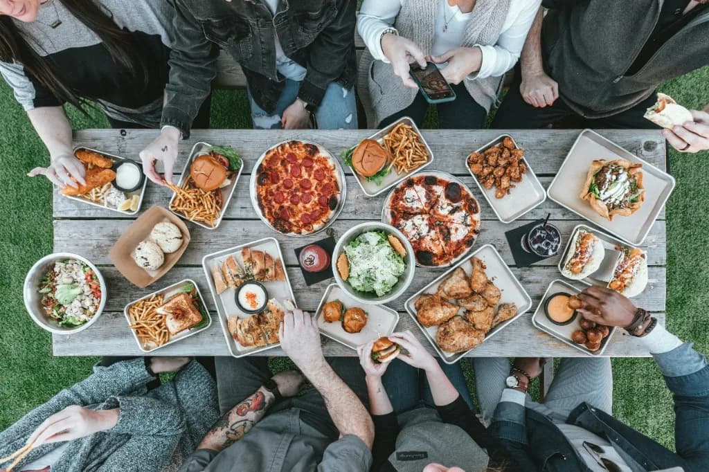 Repas convivial d'un grand groupe en extérieur.